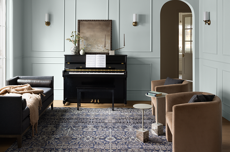 A light blue-gray painted living room with decorative wall molding, a white ceiling, and neutral decor.